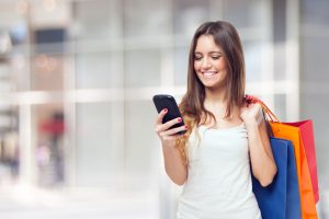 Young woman holding shopping bags looking at her phone