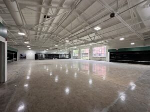 Inside photo of future grocery store. White industrial ceilings with the future produce section to the right and freezer section on the adjacent wall.