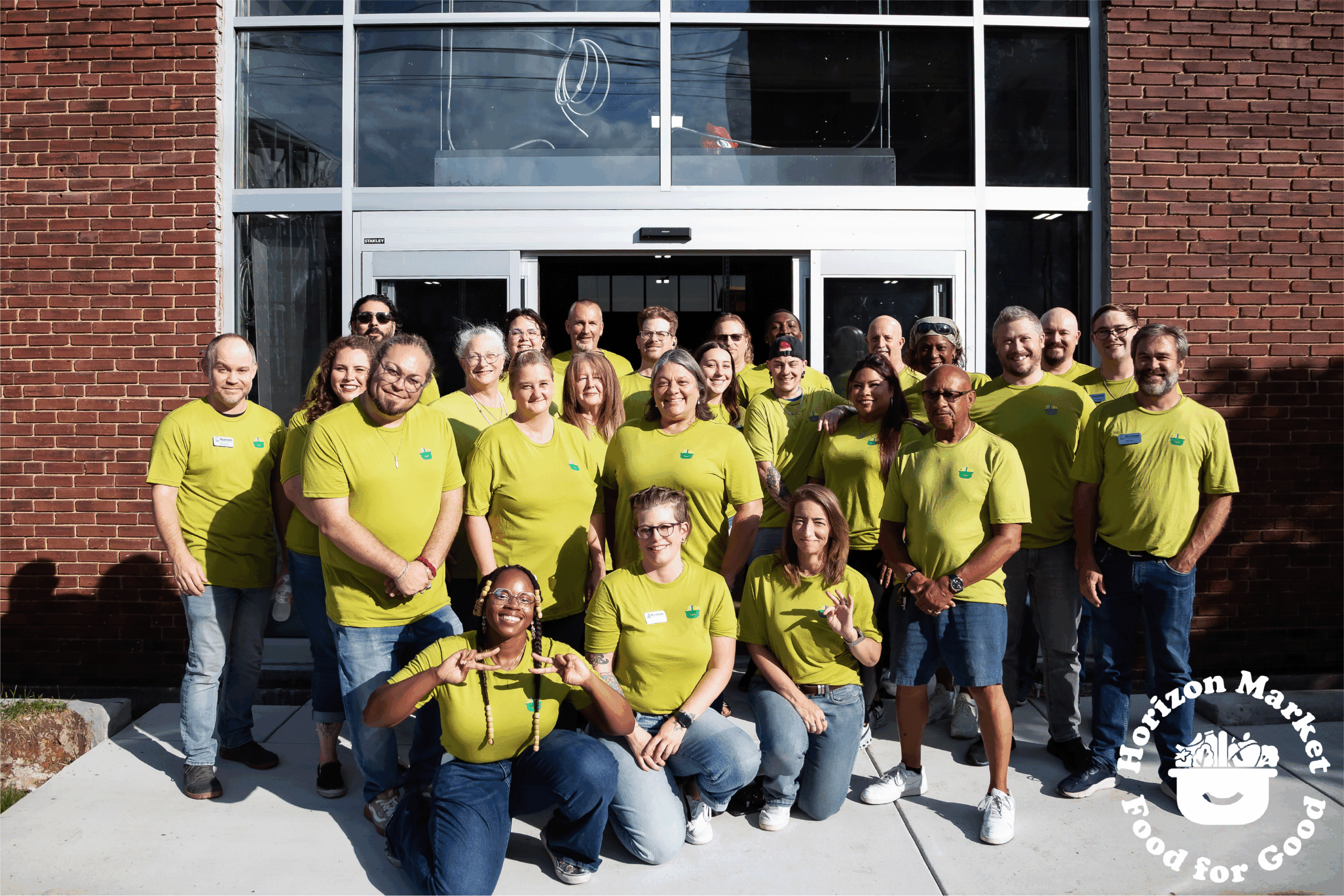 Horizon Market team members all in matching shirts gathered together at the front of the future grocery store. 